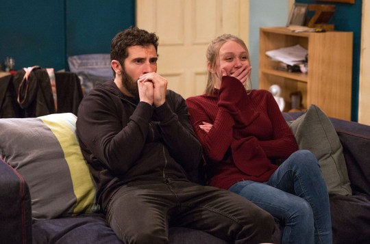 Ross Barton and Rebecca White watching a film in Emmerdale, covering their mouths with their hands