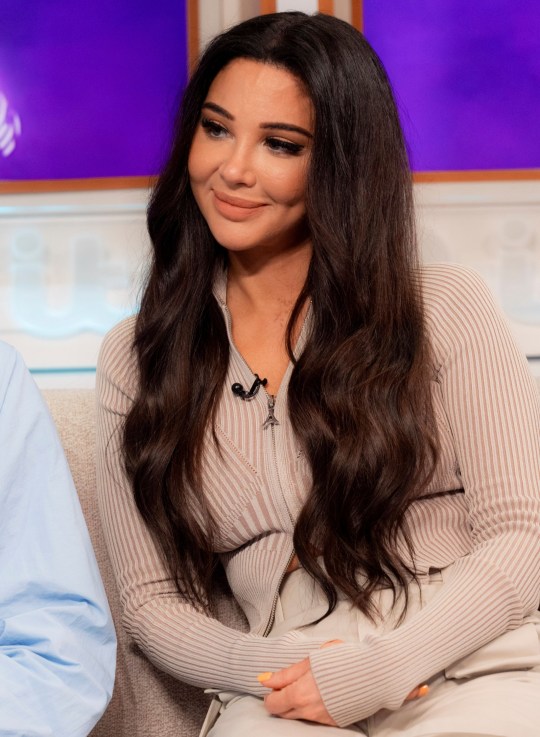 Tulisa Contostavlos smiles while on Good Morning Britain in 2023, wearing a beige zip-up top and trousers