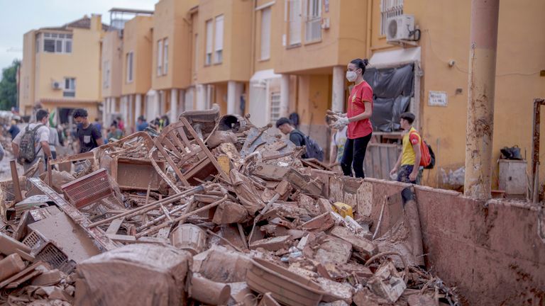 A woman stacks belongings covered in mud from a house in Catarroja, Spain.
Pic AP