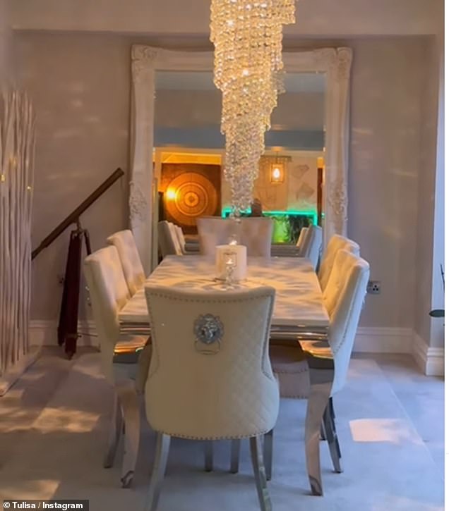 Builders had installed a huge cascading chandelier above the six seat dining table which stood in front of a mirror and it nearly spans the whole of the back wall