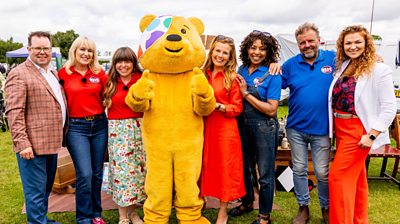 Thomas Forrester, Nicki Chapman, Briony Williams, Pudsey Bear, Christina Trevanion, Jacqui Joseph, Martin Roberts, Irita Marriott smiling to camera