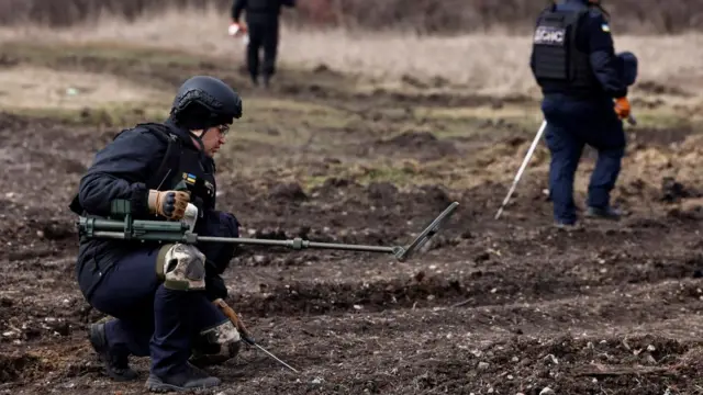 Members of the de-mining department of the Ukrainian Emergency Services check an area with equipment used to find mines