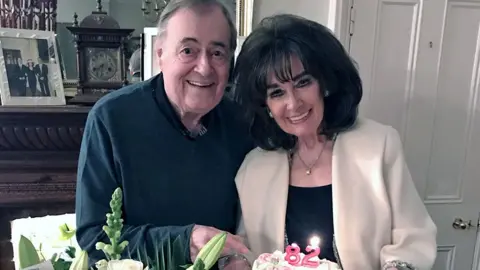 Prescott Family/PA Media Prescott next to his wife, Pauline. Both are smiling and she is holding a birthday cake with two candles with the numbers 8 and 2