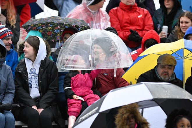 People huddle under umbrellas to keep dry during the annual Thanksgiving Day football game at Memorial Field in Natick, Thursday, Nov. 28, 2024. Natick High School defeated Framingham High School 42-15.