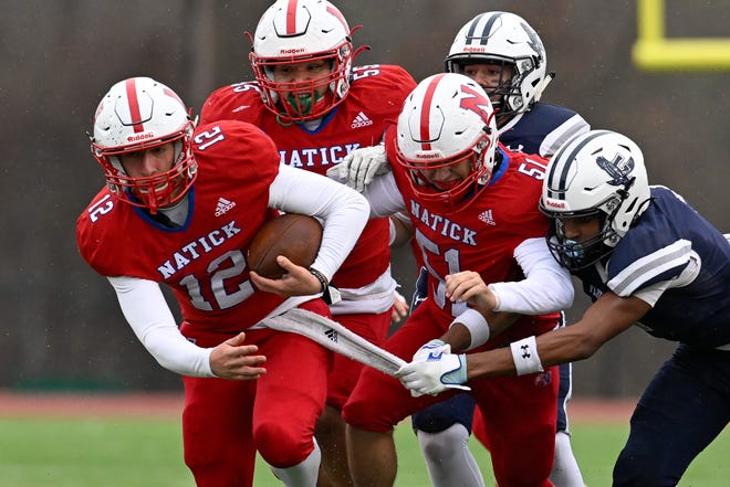 Natick junior Jesse Gagliardi runs the ball as Framingham sophomore William Owens Jr. grabs hold of the towel used to keep the ball dry during the annual Thanksgiving Day football game at Memorial Field in Natick, Thursday, Nov. 28, 2024. Natick High School defeated Framingham High School 42-15.