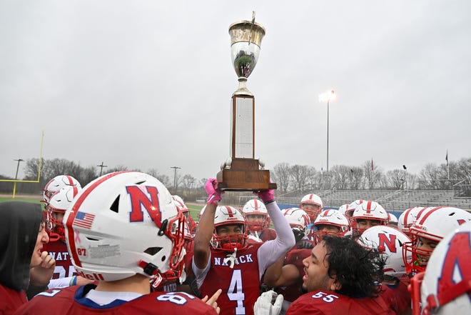 Natick senior Erick Ferro holds up the Elks trophy after defeating Framingham, 42-15, during the annual Thanksgiving Day football game at Memorial Field in Natick, Thursday, Nov. 28, 2024.