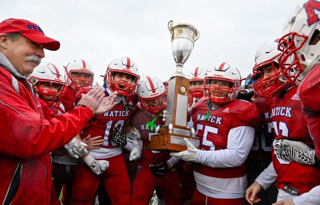 Natick senior Jordi Carias celebrates with the Elks trophy after defeating Framingham, 42-15, during the annual Thanksgiving Day football game at Memorial Field in Natick, Thursday, Nov. 28, 2024.