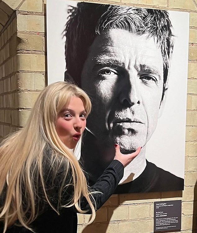 Noel Gallagher daughter Anais poses playfully by her father¿s photograph at Zoe Law¿s Legends exhibition at the National Portrait Gallery