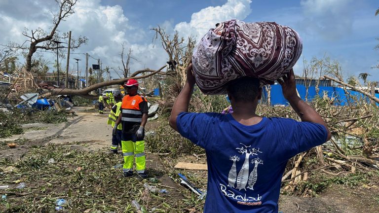 A man carries his belongings as rescuers try to clear a road in Labattoir, Mayotte. Pic: Reuters