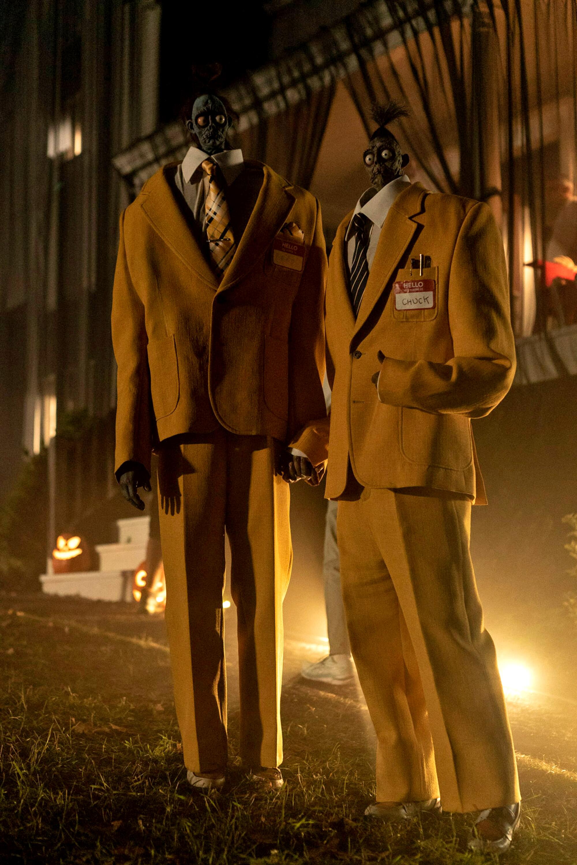 Two afterlife beings with shrunken heads wear gold suits in 