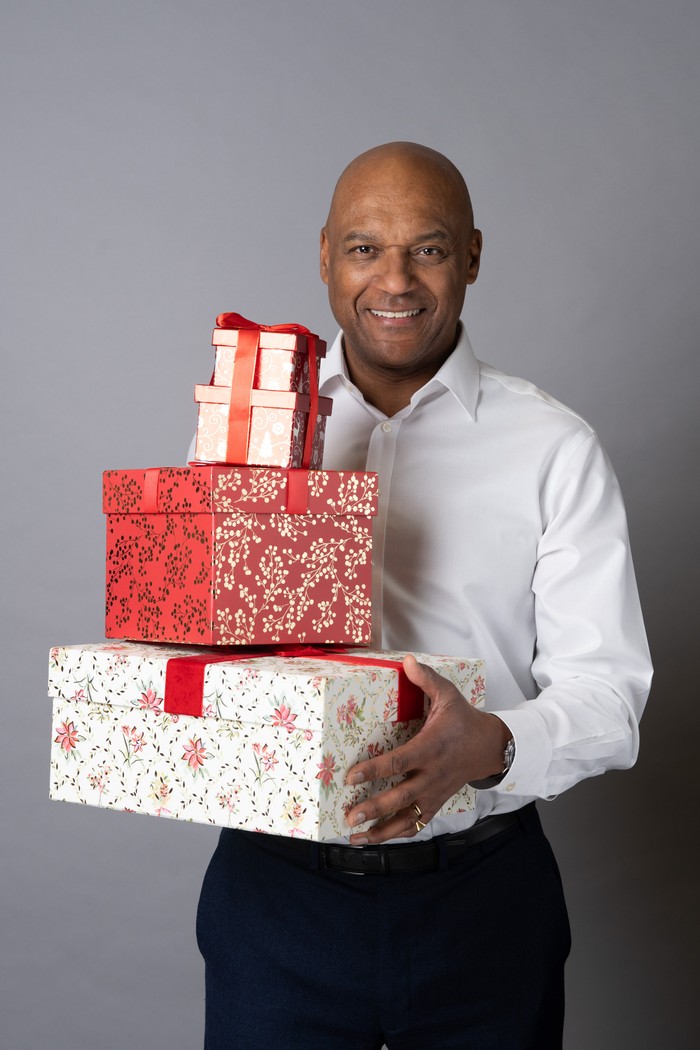 Colin Salmon poses as George Knight holding Christmas presents in a promo shoot for EastEnders.