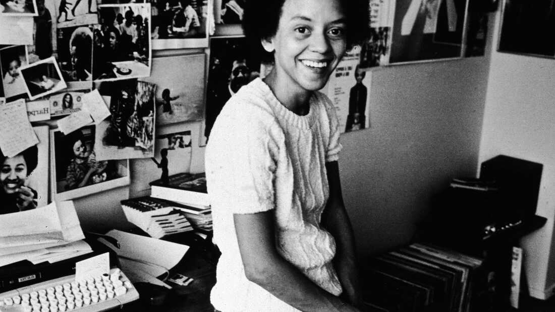 American poet Yolanda Cornelia 'Nikki' Giovanni leans on her desk beside a typewriter, in front of a wall decorated with photos, 1973. (Photo by Hulton Archive/Getty Images)