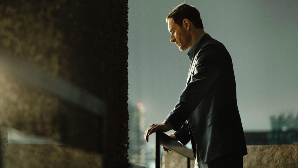 A man in formal attire leaning on a railing at night