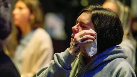 Reuters A woman holds a tissue to her face while praying for the victims and survivors of a US school shooting