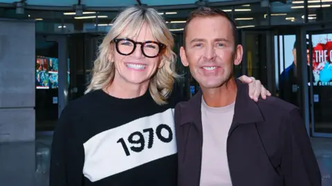 Zoe Ball and Scott Mill pictured smiling outside the BBC's New Broadcasting House in London