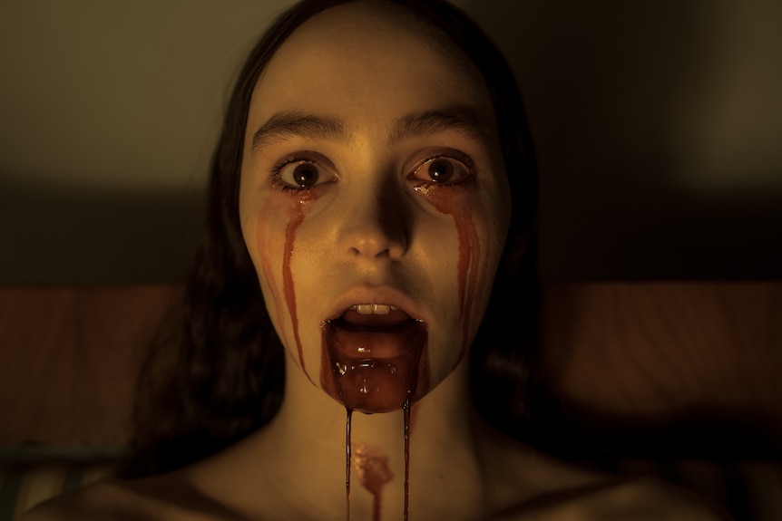 A close up of a woman's face with blood coming out of her eyes and mouth.