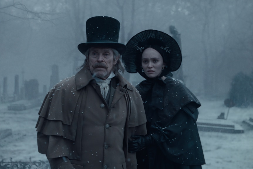 A man and a woman in Victorian clothes stand in the snow.