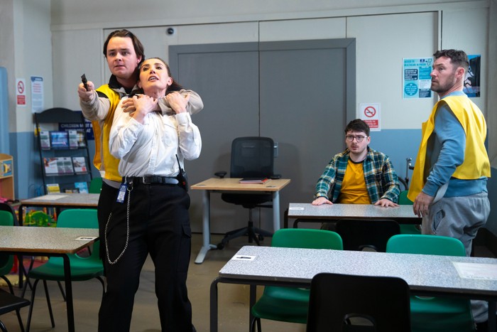 Matty holding a knife and capturing a prison guard as Bobby looks on in Coronation Street