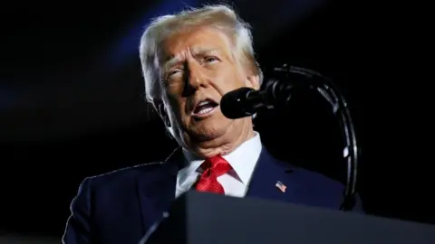 Reuters US President Donald Trump is seen standing at a podium behind a microphone